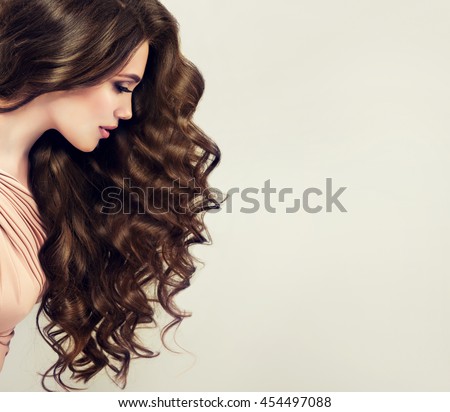 Brunette  girl with long  and   shiny wavy hair .  Beautiful  model with curly hairstyle Royalty-Free Stock Photo #454497088