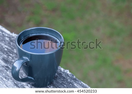 Close up of a black coffee cup on a deck railing, selective focus
