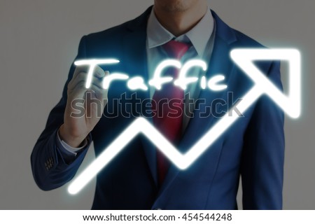 Businessman drawing TRAFFIC and upward graph arrows forward
