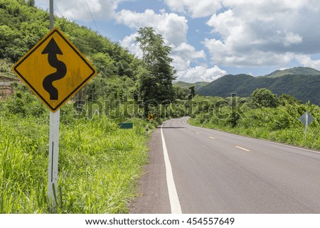 Winding road sign with mountain and sky in thailand