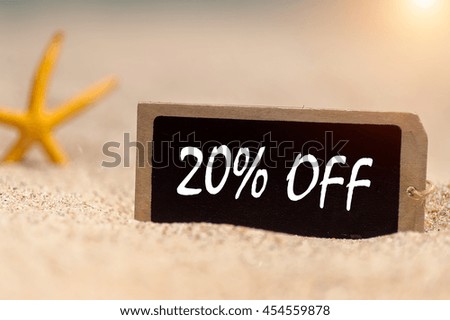 wooden board with text 20% off on sunny sandy beach. 