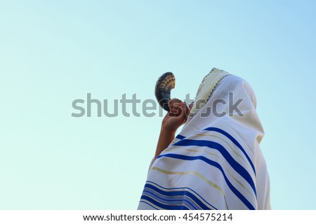 Jewish man blowing the Shofar (horn) of Rosh Hashanah (New Year). Religious symbol.

 Royalty-Free Stock Photo #454575214