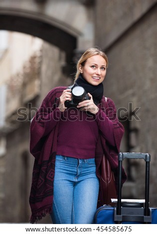 Young charming happy woman looking curious and taking pictures outdoors