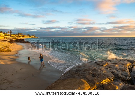Man playing with his dog at  a beach at sunset