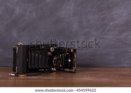 Old vintage camera against a dirty blackboard background