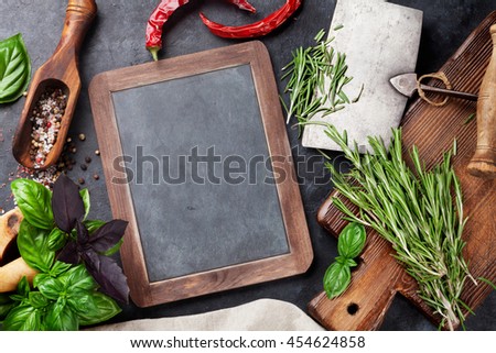 Herbs and spices cooking on stone table. Basil, rosemary, pepper and salt. Top view with blackboard for your text