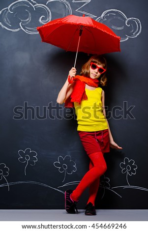 Joyful teen girl in colorful clothes stands under bright umbrellas. Summer inspiration. 