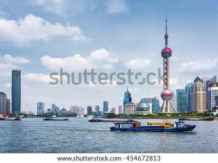 Boats crosses the Huangpu River in Shanghai, China. View from the Bund. The Oriental Pearl Tower is visible at right. Shanghai is a popular tourist destination of Asia and a global financial center.