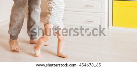 baby steps with the help of his mother Royalty-Free Stock Photo #454678165