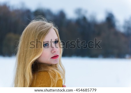 Young attractive girl in yellow dress posing on winter snowy glade