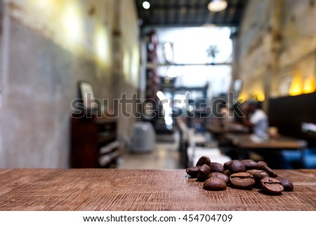 vintage picture tone Roasted brown coffee beans on a wooden table with coffee cafe shop background