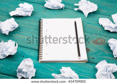 Creativity concept - notepad, pencil and crumpled paper on blue wooden table