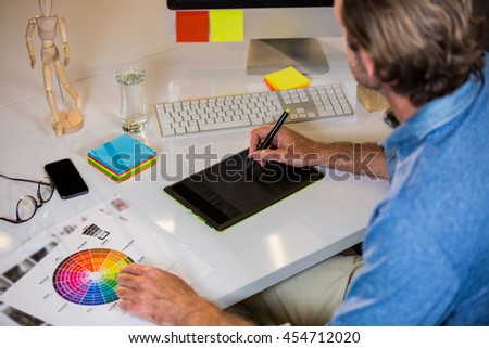 High angle view of businessman using graphics tablet at desk in creative office