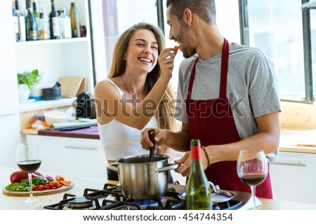 Portrait of happy young couple cooking together in the kitchen at home. Royalty-Free Stock Photo #454744354
