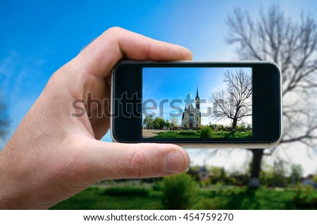 photo on the phone, the person photographed on a smartphone from the side. beautiful landscape with a standing Christian church. selfie