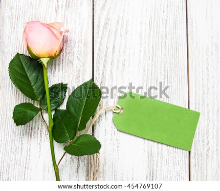 Pink rose and green tag on a old wooden background