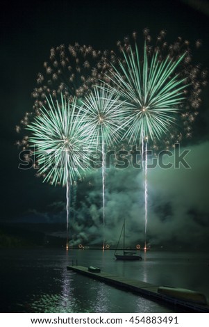 Ignis Brunensis green silver gold colored fireworks resembling aster flower reflecting on dam water surface. Long exposure night graphical photography using creative tilt effect by tilt-shift lens.