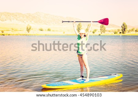 Young woman learning how to paddleboard on small pond.
