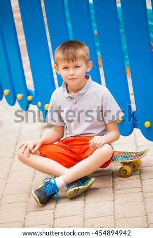 Boy sitting on a skateboard on a blue background