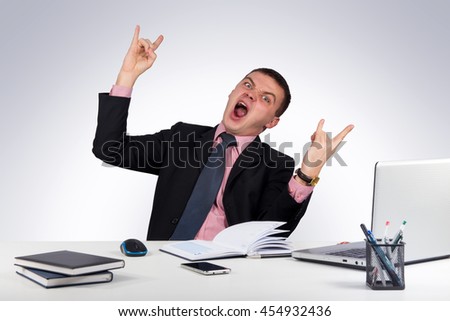 Office, finances, internet, business, success and stress concept-man in a black suit with a tie showing rock hand gesture