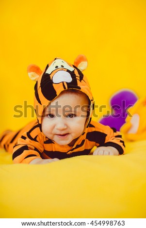 gorgeous child in a suit of a tiger lies on a bed