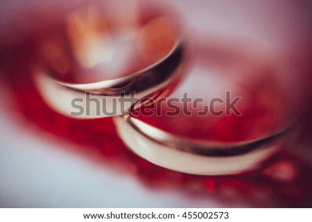 A blurred picture of wedding rings lying on the red table