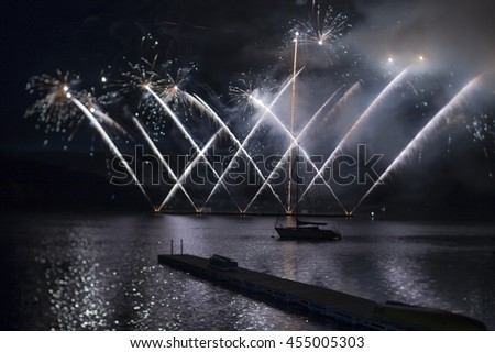 Ignis Brunensis blue silver and gold colored fireworks resembling aster flower reflecting on dam water surface. Long exposure night graphical photography using creative tilt effect by tilt-shift lens.