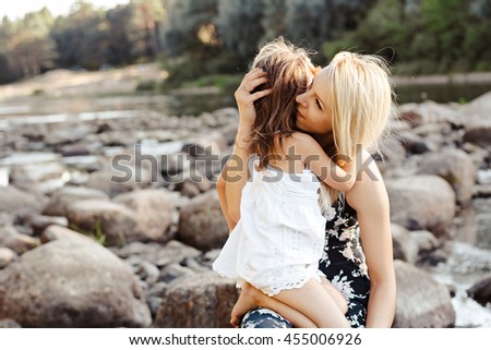 mother and daughter in front of a river, on the rocks. 