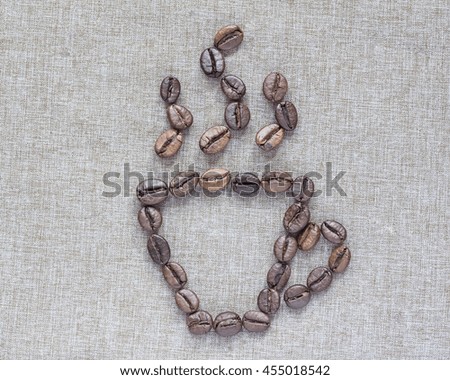 Cup of coffee beans on linen background