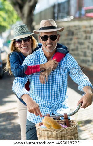 Portrait of mature couple hugging while riding bicycle in city