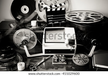 Desktop workspace for vintage movie editing with film reels, editing machine, splice, clapper in black and white