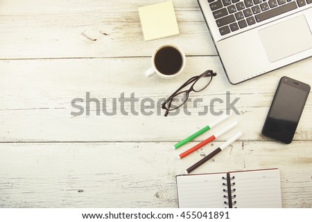 Office workspace with keyboard notepad coffee of cup and smartphone on wood table.