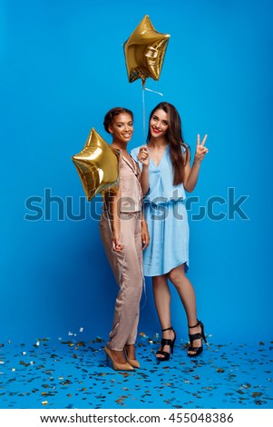 Portrait of two girls resting at party over blue background.