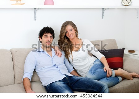 young couple sitting in the living room and looks at the camera pose