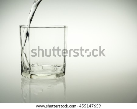 Pouring glass of water with reflect on gray background