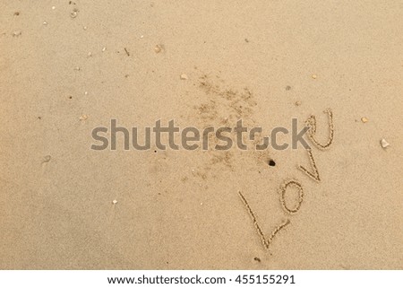 written words "Love" on sand of beach