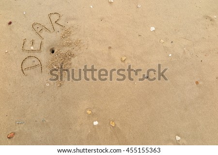 written words "DEAR" on sand of beach