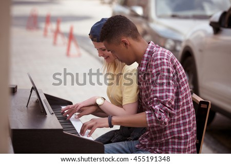 Closeup picture of man and woman playing piano outdoors all together. People playing and singing songs. Keyboard of piano concept.