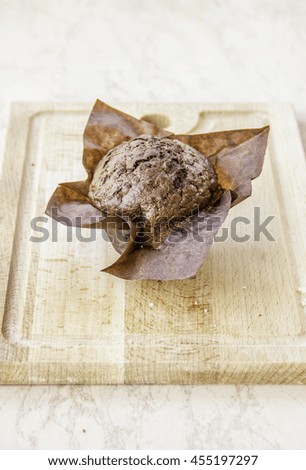 sweet isolated chocolate cupcake without cream on wooden desk 