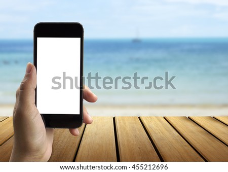 Closeup of women's hands holding cell telephone with empty copy space screen for your advertising text message or promotional content with the beach background.