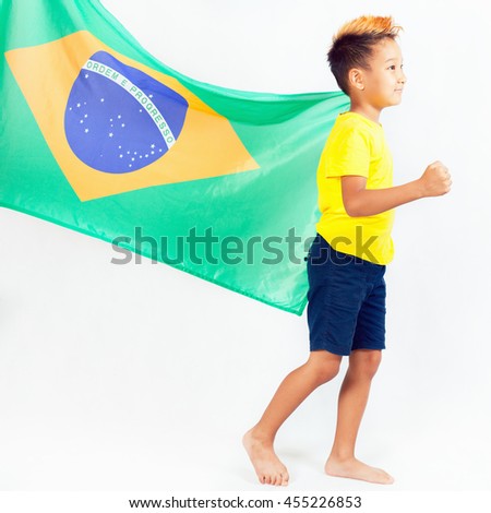 Brazilian patriot boy walking and holding Brazil flag and torch. Football or soccer championship. Support fan. White background