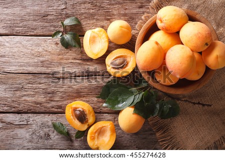 Delicious ripe apricots in a wooden bowl on the table close-up. Horizontal view from above Royalty-Free Stock Photo #455274628