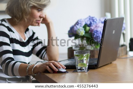 Attractive middle-aged blonde businesswoman working, using portable computer, looking at the monitor Royalty-Free Stock Photo #455276443