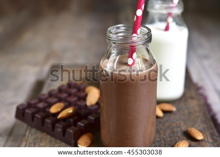 Chocolate and regular milk in a vintage bottles with paper straws on a rustic wooden background.
