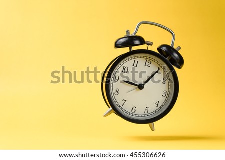 black vintage alarm clock falling on the floor with color background