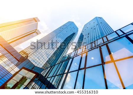 Bottom wide angle view of modern skyscrapers in business district in beautiful evening light at sunset with monochrome retro vintage Instagram style filter and lens flare sunlight effect Royalty-Free Stock Photo #455316310