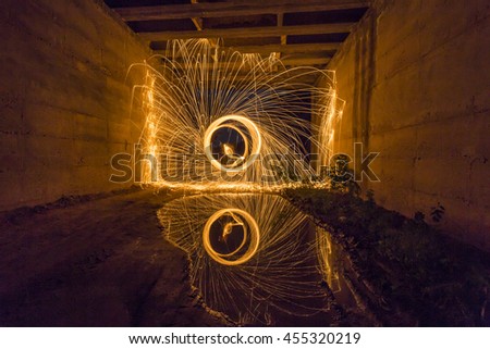 Steel wool spinning reflected in the water under a bridge