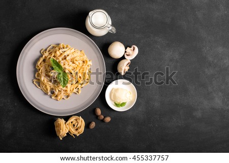 Pasta with mushrooms and bechamel sauce. Ingredients for spaghetti on a black background.  Copy space for your text Royalty-Free Stock Photo #455337757