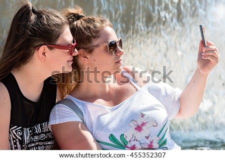 two sisters make selfie near fountain 