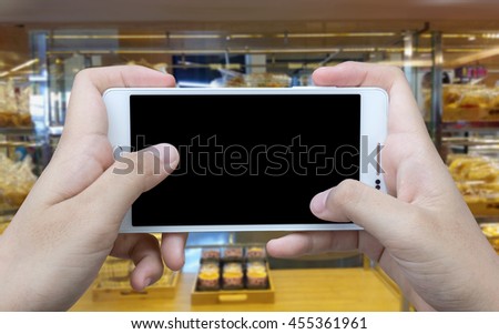 Girl use mobile phone, blur image of  bakery shop as background.